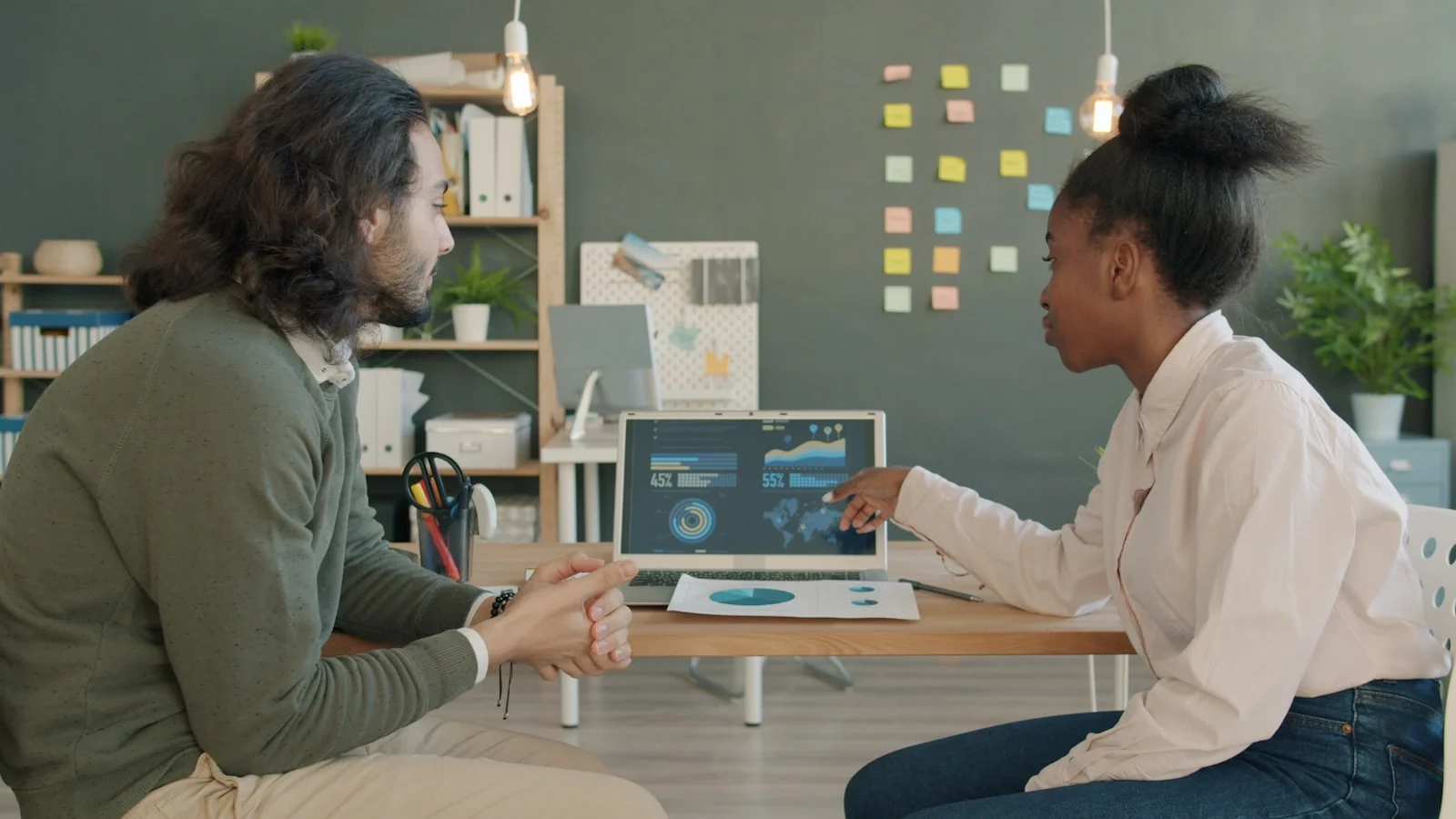 Two colleagues discussing data on a laptop screen. Two colleagues discussing data on a laptop screen.