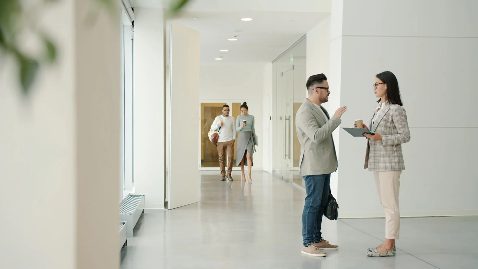 Two people talking in a modern office hallway. Two people talking in a modern office hallway.